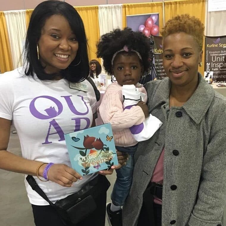 Jenne holding Once Upon a Preemie book and a lady holding a child